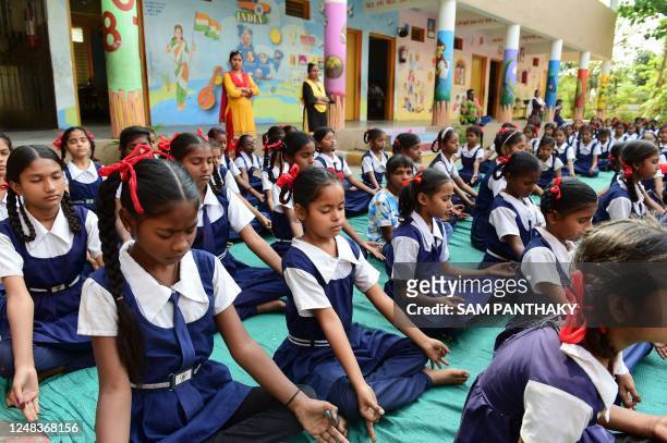 Schoolgirls meditate during a martial arts class for self-defence at a school in Ahmedabad on March 16, 2023.