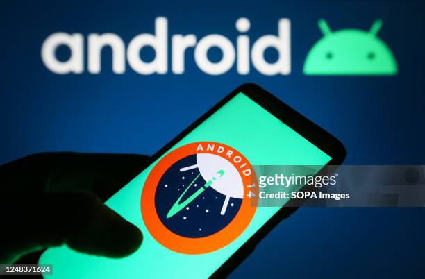In this photo illustration, Android 14 logo of a mobile operating system is seen on a smartphone and Android logo on a pc screen.