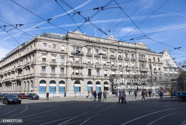 People walk past the global headquarters of Swiss bank Credit Suisse the day after its shares dropped approximately 30%, on March 16, 2023 in Zurich,...