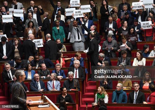 Members of Parliament of left-wing coalition NUPES hold placards during the speech of France's Prime Minister Elisabeth Borne , as she confirms to...