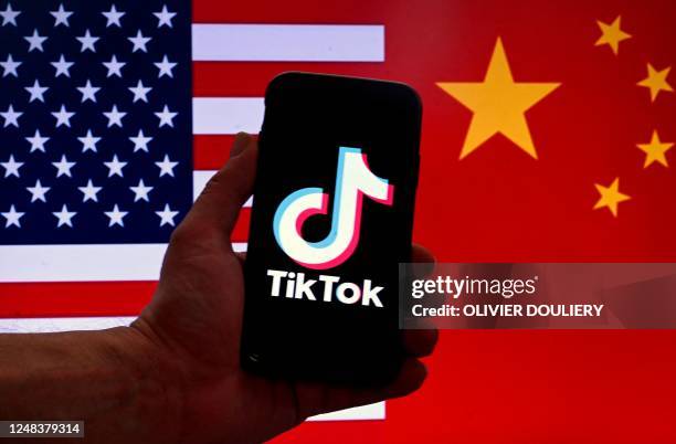 In this photo illustration the social media application logo for TikTok is displayed on the screen of an iPhone in front of a US flag and Chinese...
