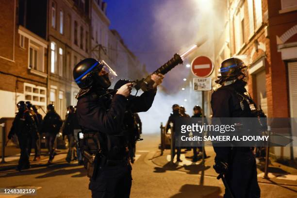 French police officer in riot gear fires a tear gas canister launcher during a demonstration after the French government pushed a pensions reform...