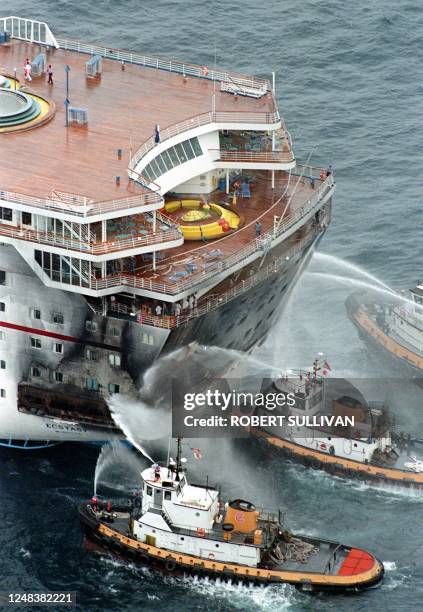 Fire boats pour water on the rear of The Ecstasy, a ship owned by Carnival Cruise Lines 20 July on the Atlantic ocean off Miami Beach, FL. The ships...