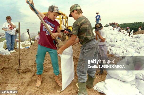 Cody Cook and Nick Hoffman fill sandbags as brother Dustin Hoffman takes a break 10 July 1993 at a strained levee along the rising Mississippi River...