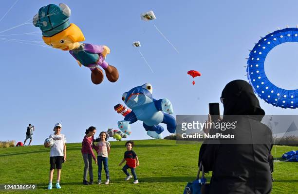 Children pose for a photo in front of giant kites during the inaugural day of the 2023 Qatar Kite Festival at the Museum of Islamic Art Park Hills in...
