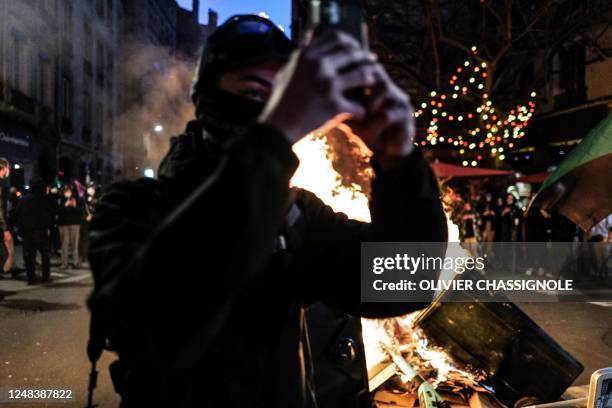 Protester takes a selfie next to a fire during a demonstration after the French government pushed a pensions reform through parliament without a...