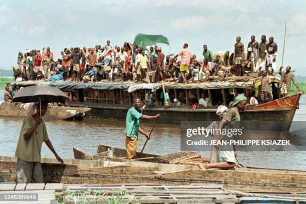 CAnoe passes an overloaded ferry boat 13 December on the Congo River at Kinshasa, where transport between the capital of the Democratic Republic of...