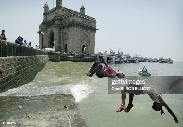 Indian street children take to the water doing back flips, as they seek relief from extreme hot weather conditions in Bombay, 06 May 2004, near one...