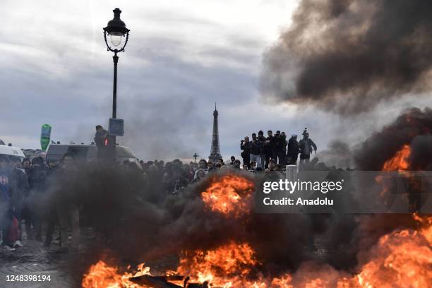 March 16: Eiffel Tower is seen while protesters set fire as clashes take place with riot police during a demonstration against French government's...