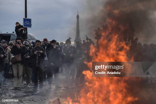 March 16: Eiffel Tower is seen while protesters set fire as clashes take place with riot police during a demonstration against French government's...