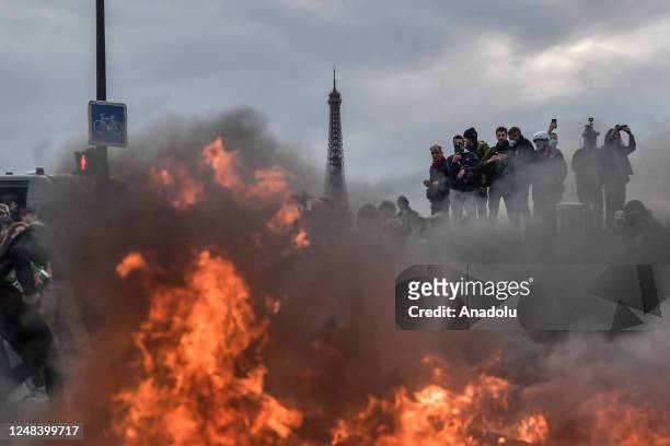 March 16: Eiffel Tower is seen while protesters set fire as clashes take place with riot police during a demonstration against French government's...