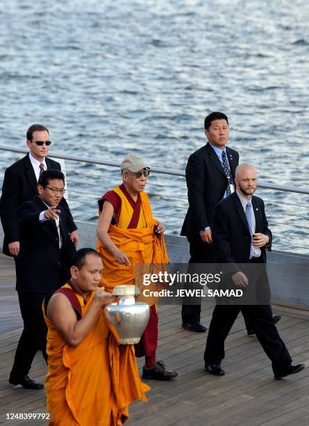 Tibetan spiritual leader the Dalai Lama is flanked by security personnel as he arrives to bless the Anacostia River in Washington with sand from a...