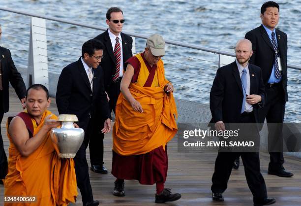 Tibetan spiritual leader the Dalai Lama is flanked by security personnel as he arrives to bless the Anacostia River in Washington with sand from a...