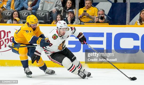 Tyler Johnson of the Chicago Blackhawks skates the puck in on net against Dante Fabbro of the Nashville Predators during an NHL game at Bridgestone...