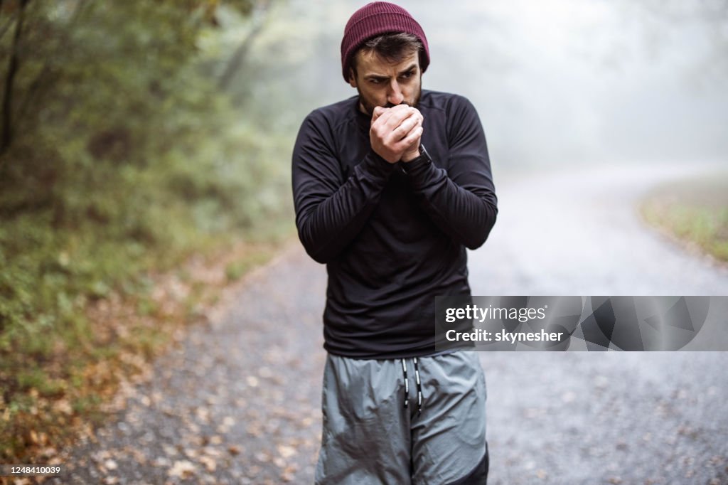 Young man warming his hands during cold in nature.
