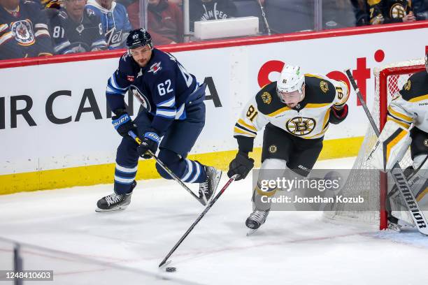 Dmitry Orlov of the Boston Bruins plays the puck around the net as Nino Niederreiter of the Winnipeg Jets gives chase during first period action at...