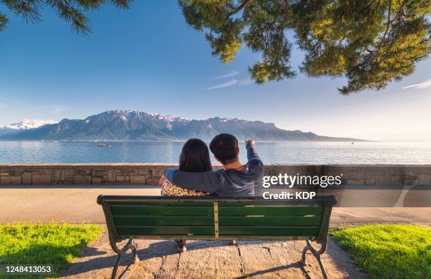 portrait of couple love tourist are sitting in public garden bench while looking at beautiful scenic nature landscape at lake geneva, vevey, switzerland. - geneva switzerland imagens e fotografias de stock