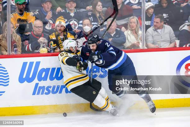 Dylan DeMelo of the Winnipeg Jets lays a hit on Brad Marchand of the Boston Bruins during second period action at the Canada Life Centre on March 16,...