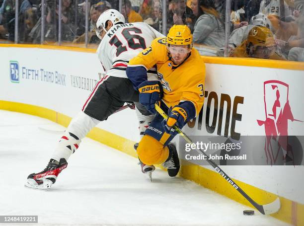 Jeremy Lauzon of the Nashville Predators tries to clear the puck against Jujhar Khaira of the Chicago Blackhawks during an NHL game at Bridgestone...