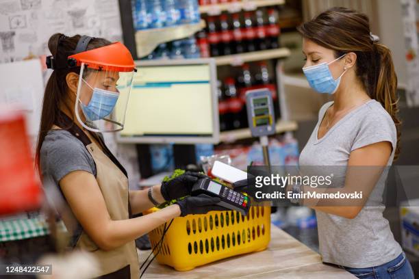female customer doing a contactless payment at the supermarket - debit cards credit cards accepted stock pictures, royalty-free photos & images
