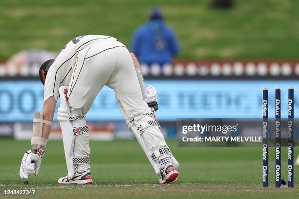 New Zealand's Kane Williamson picks up the bails after they were blown off in strong winds on day one of the second Test cricket match between New...