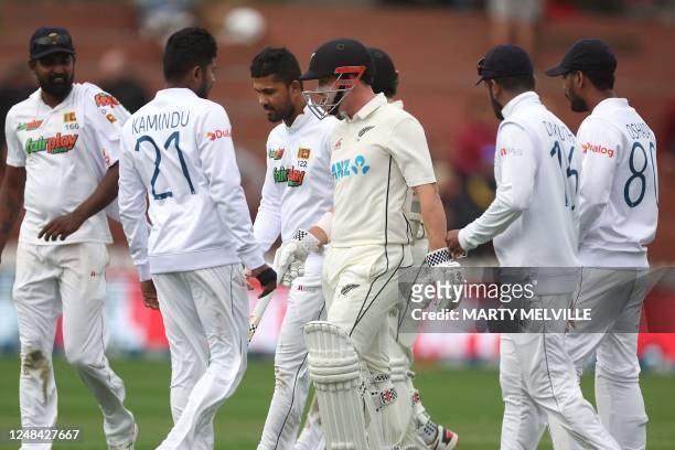 New Zealand's Henry Nicholls walks from the field with Sri Lanka players as bad light halts play on day one of the second Test cricket match between...