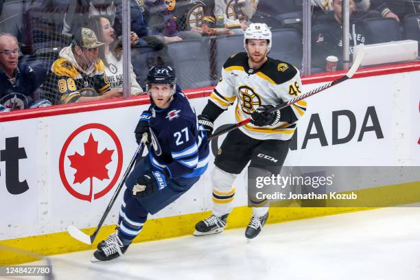 Nikolaj Ehlers of the Winnipeg Jets and Matt Grzelcyk of the Boston Bruins keep an eye on the play during third period action at the Canada Life...