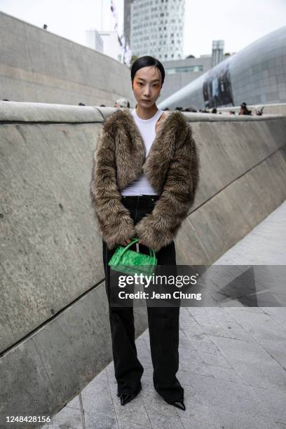 Jerry wears a faux fur jacket from Neuter and a neon green Find Kapoor mini bag at Seoul Fashion Week AW 23 on March 17, 2023 in Seoul, South Korea.