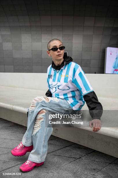 Kim Seong-ju wears a blue striped soccer jersey from Ajobyajo and pink sneakers from Nike x Jaquemus at Seoul Fashion Week AW 23 on March 17, 2023 in...