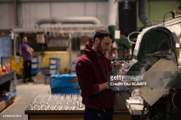 Employee Ben Seale works to finish the rim of a lead crystal wine glass being created being created in Cumbria Crystal's factory in Ulverston near...