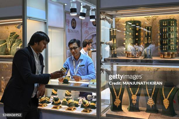 An employee of a jeweller shows gold jewellery to a visitor during the 1st India International Jewellery Show organised by the Gem and Jewellery...