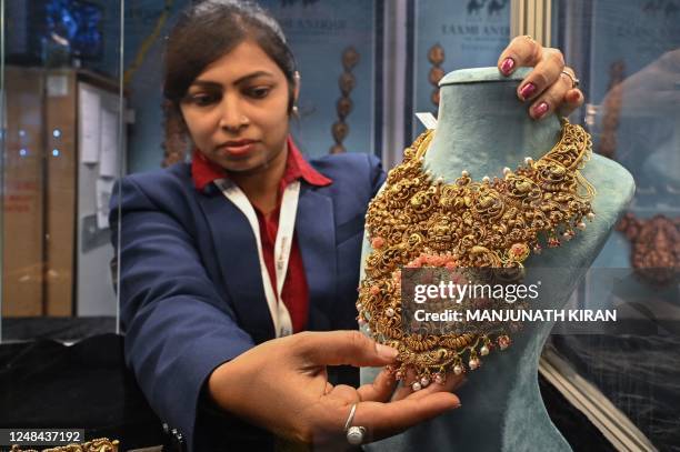 An employee of a jeweller arranges a gold necklace on display during the 1st India International Jewellery Show organised by the Gem and Jewellery...