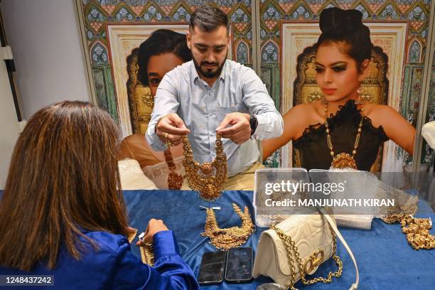 An employee of a jeweller shows a gold necklace to a visitor during the 1st India International Jewellery Show organised by the Gem and Jewellery...