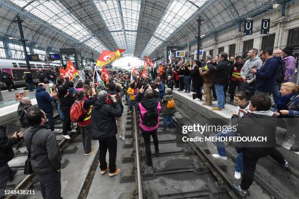 Unionists of the railway sector and protesters stand on the tracks during a demonstration a day after the French government pushed a pensions reform...