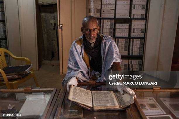 Abdullah Habbot wears gloves as he handles a manuscript at his library, founded by his family over 200 years ago, in Chinguetti, on March 16, 2023...