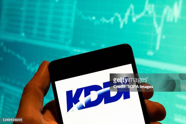 In this photo illustration, the Japanese telecommunications operator company, KDDI logo is seen displayed on a smartphone with an economic stock...