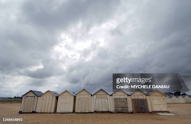 Photo des cabanons de la plage de Ouistreham désertée par les touristes en raison d'une météo maussade, le 12 août 2006. AFP PHOTO MYCHELE DANIAU