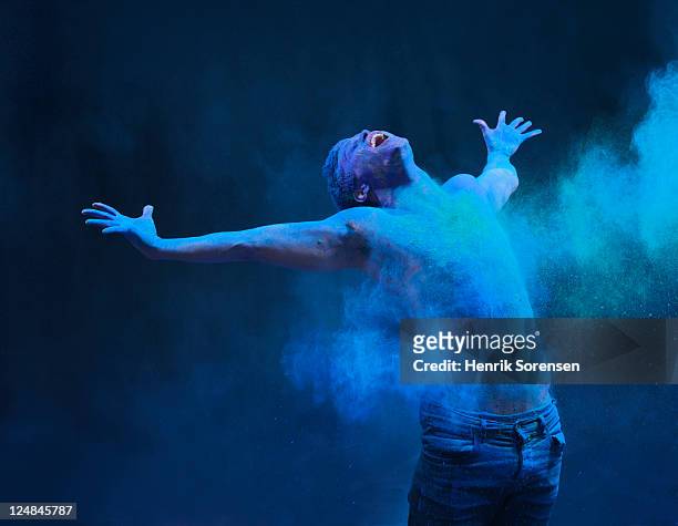 young man in spray of colored powder - body paint 個照片及圖片檔