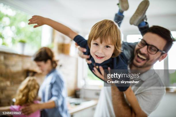 feliz chico divirtiéndose con su padre en la cocina. - felicidad fotografías e imágenes de stock