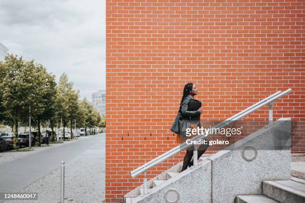 elegante vrouw die stairs in modern district in berlijn loopt - walking up stairs stockfoto's en -beelden