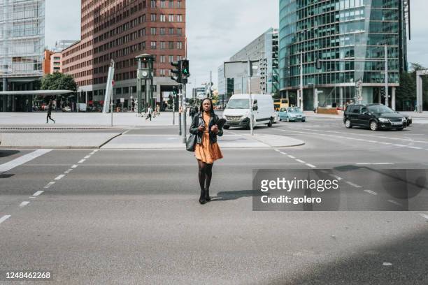 schwarze geschäftsfrau überquert straße am potsdamer platz in berlin - berlin traffic stock-fotos und bilder