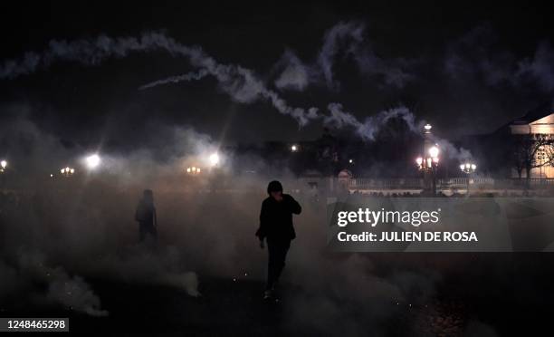 Protester runs away from teargas during during a demonstration in Lille, northern France, on March 17 the day after the French government pushed a...