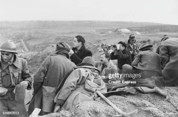 American writer Ernest Hemingway in a trench with fellow war correspondents during the Spanish Civil War, circa 1937.