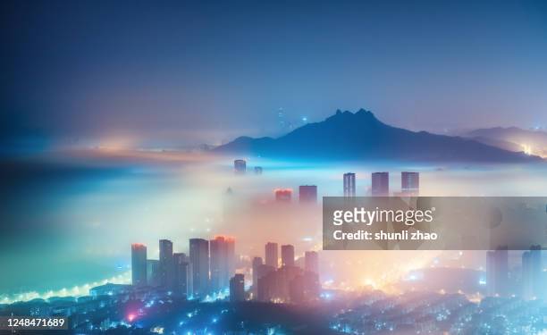city in the mist at night - qingdao stock-fotos und bilder