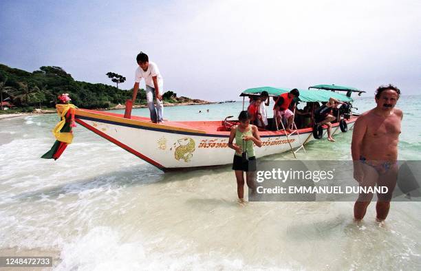 Tour boat unloads a group of tourists 26 October on a beach on this small resort island some 200 kilometers South of Bangkok. Foreign tourist...