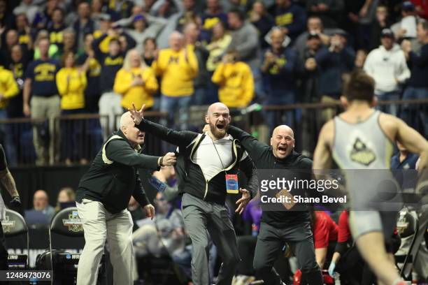 Purdue Head coach, Tony Ersland, holds back other coaches from the mat during the Matt Ramos of Purdue's win by fall over Spencer Lee of Iowa during...