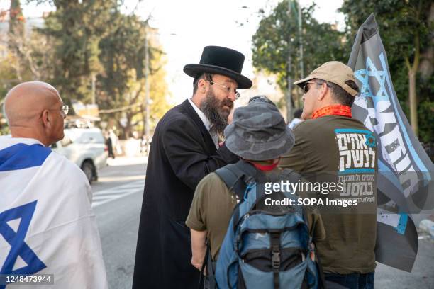 Israeli reserve soldier against the judicial overhaul speaks with an orthodox man in Bnei Brak during the demonstration . The soldiers opened a...