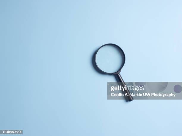 magnifying glass on blue colour background with copy space. searching information data concept - vinden stockfoto's en -beelden