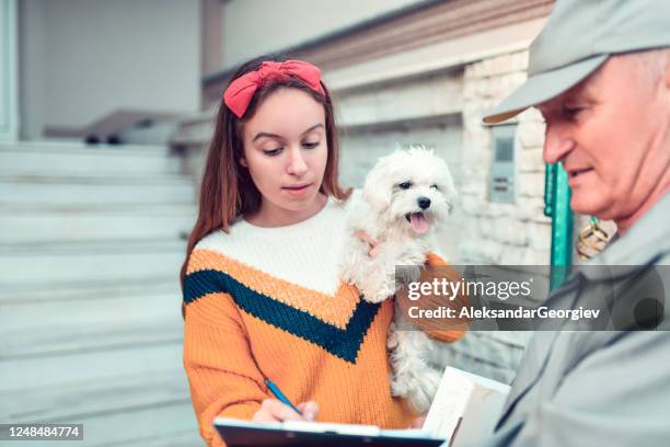 young female with puppy signing mailman's receipt - postal worker stock pictures, royalty-free photos & images