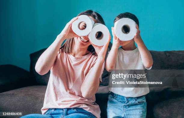 mother and son looking through rolls of toilet paper. - toilet paper stock pictures, royalty-free photos & images